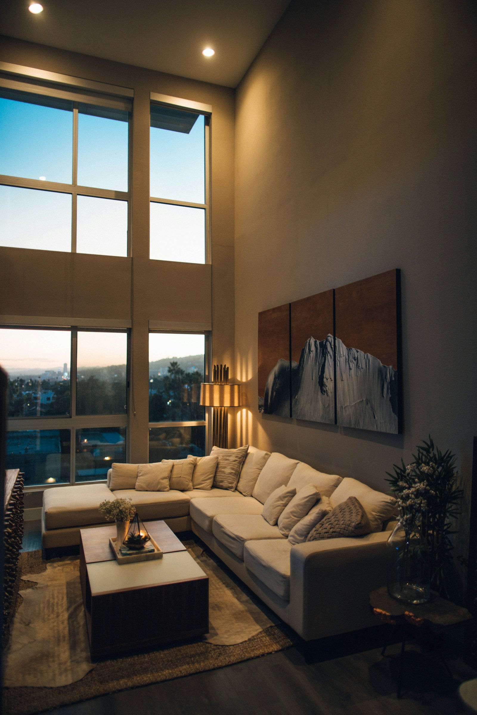 Living room at dusk with warm lamps and a sunset view